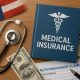 Health insurance card, stethoscope, and US flag symbolizing American medical insurance coverage